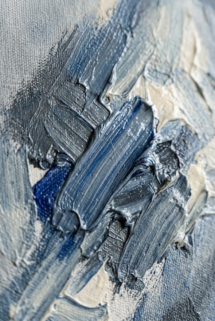 Macro detail of acrylic paint on canvas — visible brushstrokes, ridges of dusk-blue and slate pigment, the cream of unpainted canvas weave showing through